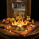 Golden brass peacock diya with five lit oil lamps for Diwali puja
