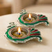 Two ornate peacock-shaped brass finish diya lamps with silver base and green red enamel for Diwali Puja decor