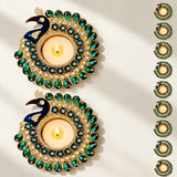 Golden peacock-themed tealight holder adorned with green blue gemstones white pearls and rhinestones for diwali pooja decor