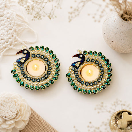 Two ornate peacock tealight candle holders with gold metal base, green and blue enamel, and rhinestones for festive decor