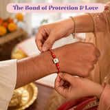 Red beaded rakhi with gold-toned square centerpiece and clear stone in raksha bandhan gift hamper set for brother and bhabhi