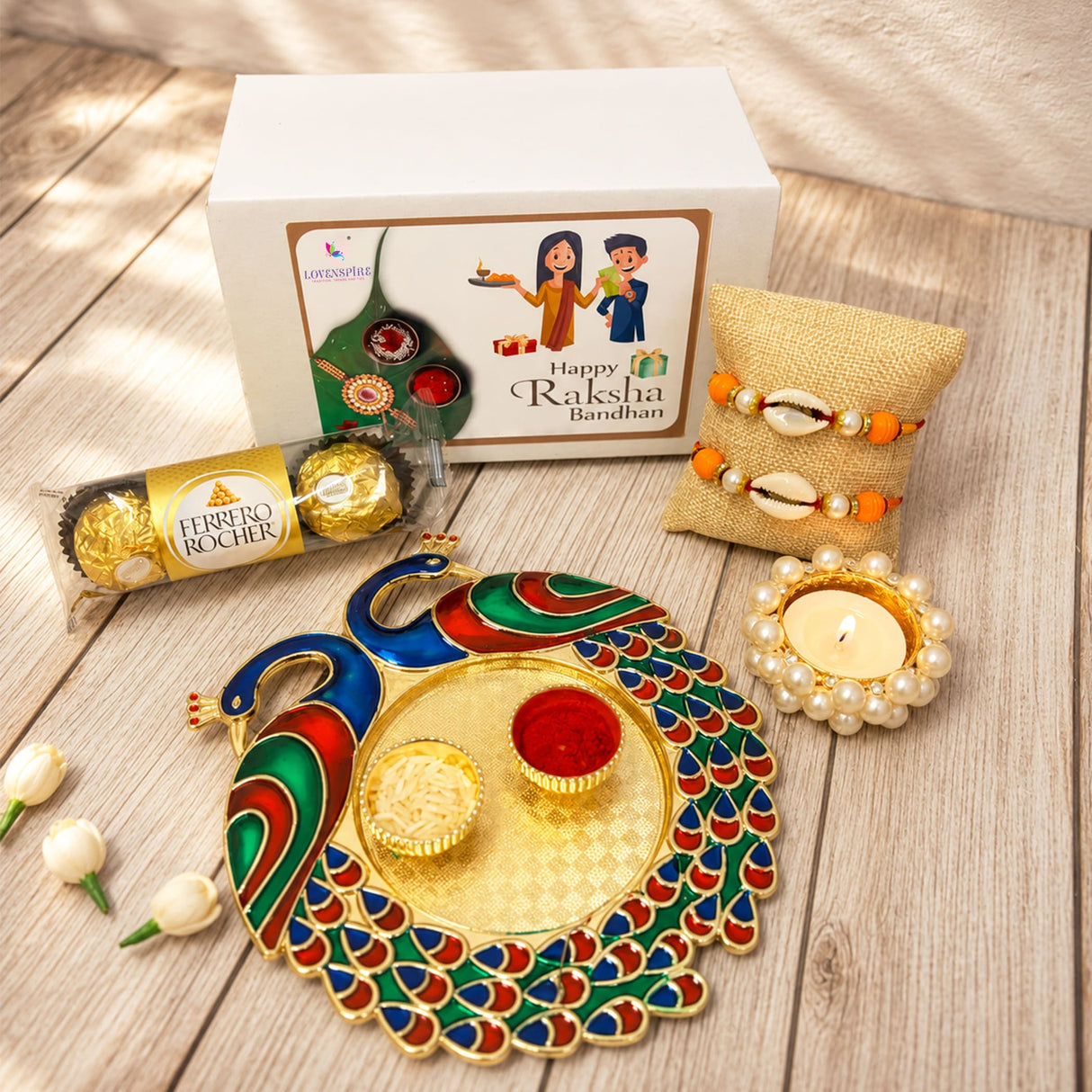 A vibrant peacock-shaped brass tray with colorful enamel and a central red bowl included in a peacock rakhi gift hamper set