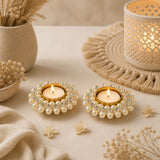 Two elegant gold-toned pearl t-light holders with clear crystals holding flickering candles for festive home decor