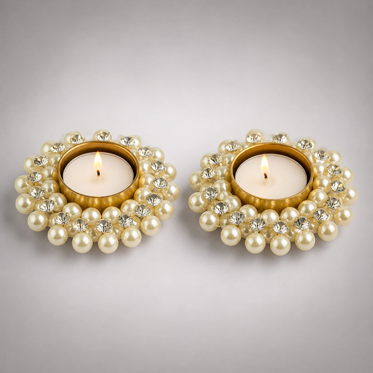Elegant gold pearl and crystal-adorned pearl t-light holders with lit candles for festive home decor and gifting