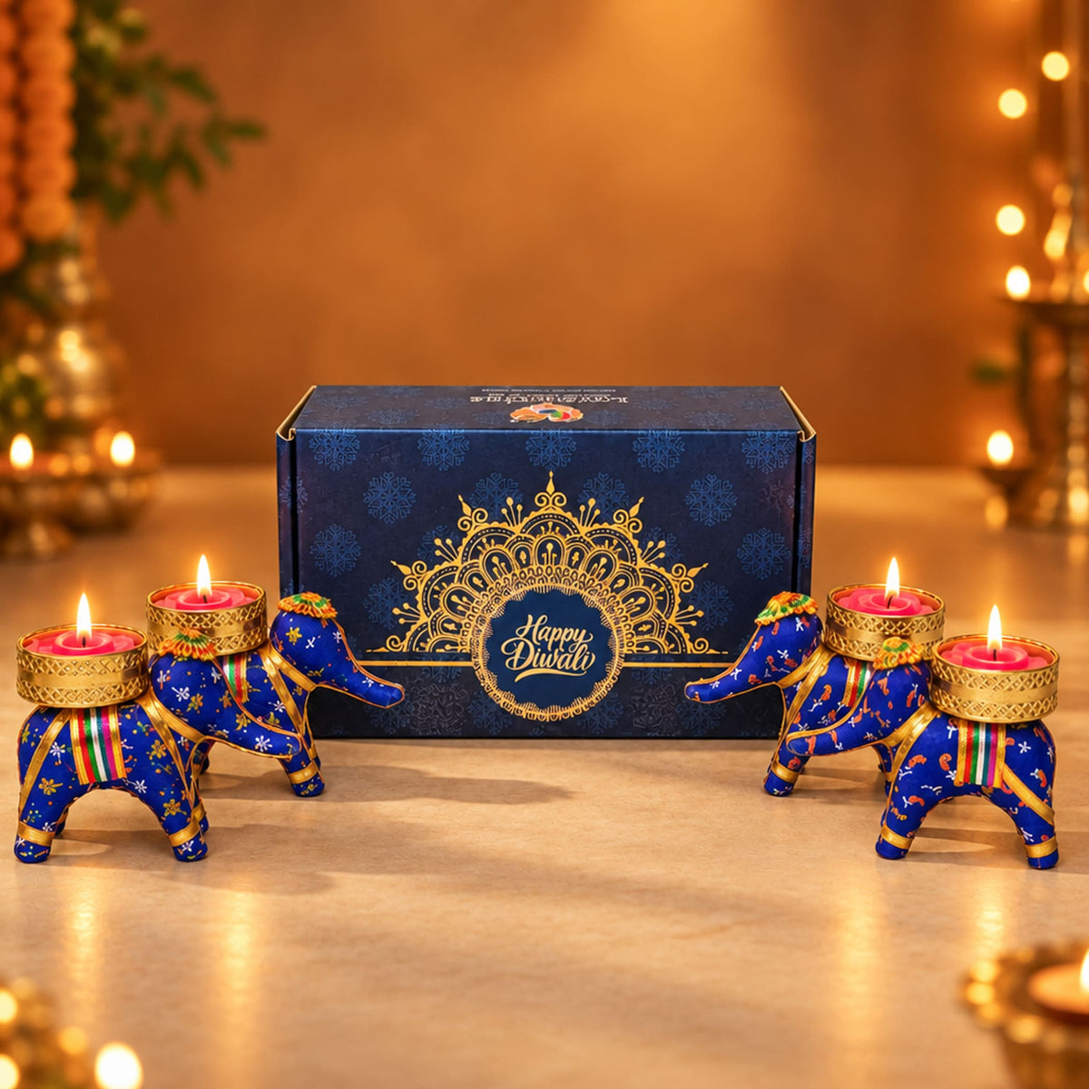 Blue elephant-shaped candle holders with gold accents and intricate patterns holding lit pink candles for diwali gifts hamper