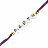 Designer custom named white circular bead rakhi bracelet with gold lettering parth and red blue braided cord for protection