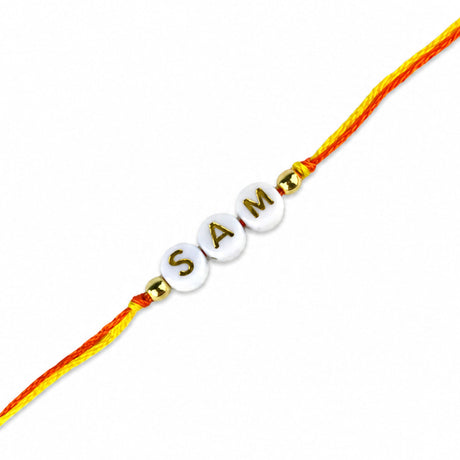 A personalized white bead rakhi with gold lettering sam and golden beads on orange and yellow twisted thread for raksha bandhan