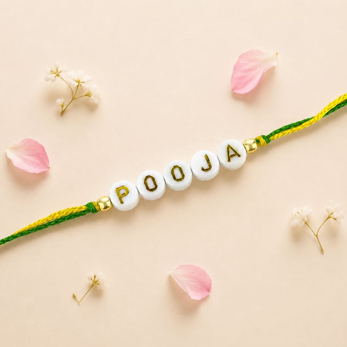 Designer custom named white beaded rakhi with gold pooja lettering and green yellow braided cord for protection and good luck