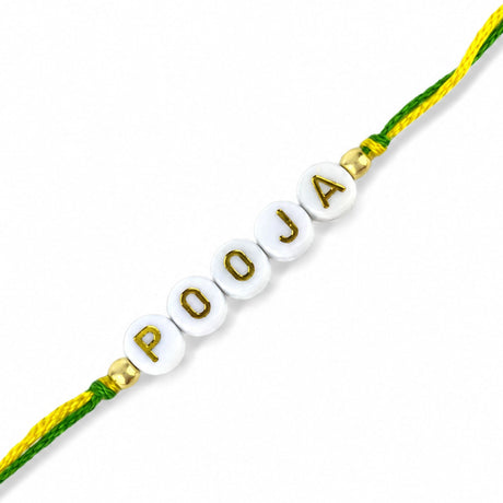 Designer custom named rakhi with white ceramic beads and gold lettering on green and yellow braided cord for raksha bandhan