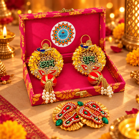 Golden diwali-themed decorative earrings with paisley and peacock designs, red fabric accents, green lettering, and pearl strands in a personalized diwali gifts hamper