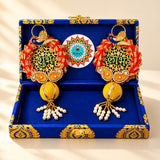 Pair of ornate red and gold peacock-themed diwali decorative earrings with intricate lacework pearl accents and tassels in a personalized diwali gifts hamper