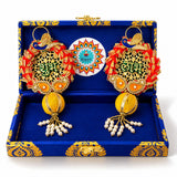 A pair of gold-toned peacock diwali decorations with red tassels and pearls in a rajasthani brocade hamper gift box