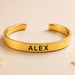 Gold-colored personalized stainless steel cuff bracelet with alex engraved in black for raksha bandhan gift
