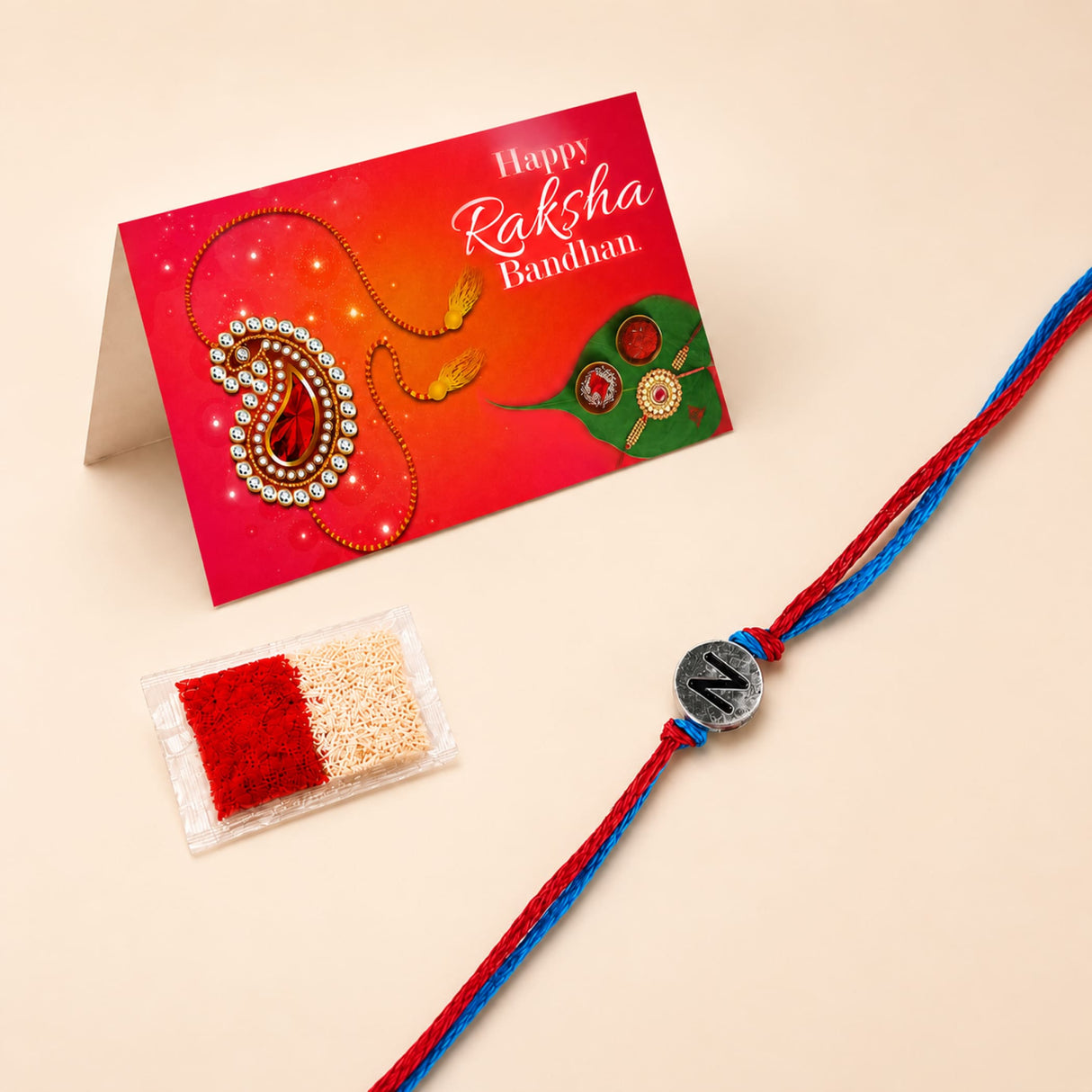 Designer custom single letter rakhi for brother and bhabhi with red and blue braided thread and silver n charm