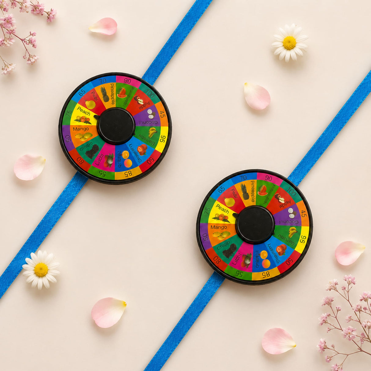 Two colorful circular fruit-themed pin wheel rakhis with black centers symbolizing protection and good luck