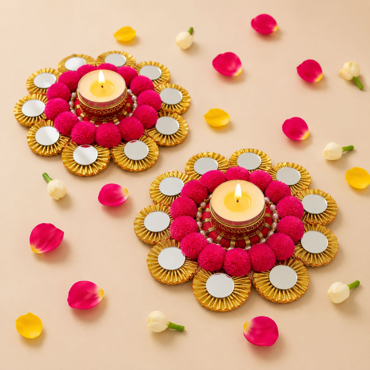 Vibrant pink pom-pom and gold mirror-adorned tea light candle holders with lit candles for festive home decor