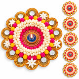 Vibrant tealight candle holder rangoli mat with pink yellow pom-poms white flowers and gold-fringed mirrors for diwali decor