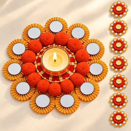 Ornamental rangoli mat tealight candle holder with central lit diya, orange pom-poms, and gold-rimmed mirrors for festive decor