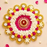 Tea light candle holder rangoli mat featuring vibrant pink white and yellow floral design with central lit diya in ornate gold stand for festive decor