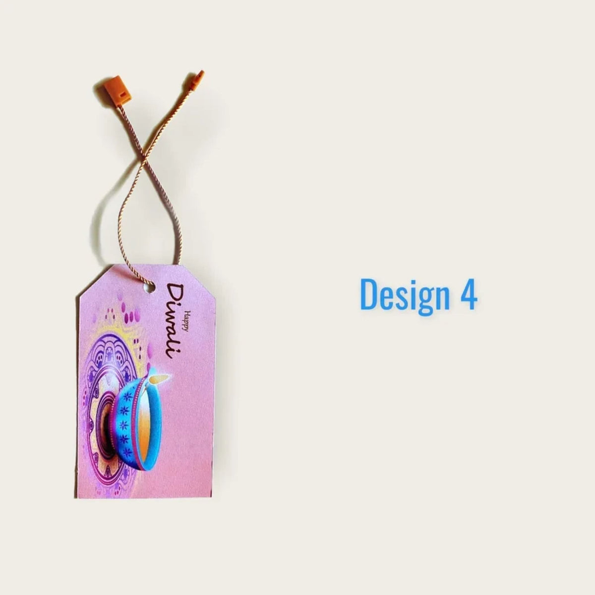 Pink rectangular paper happy diwali gift tag with blue diya design and braided string attached to orange plastic loop