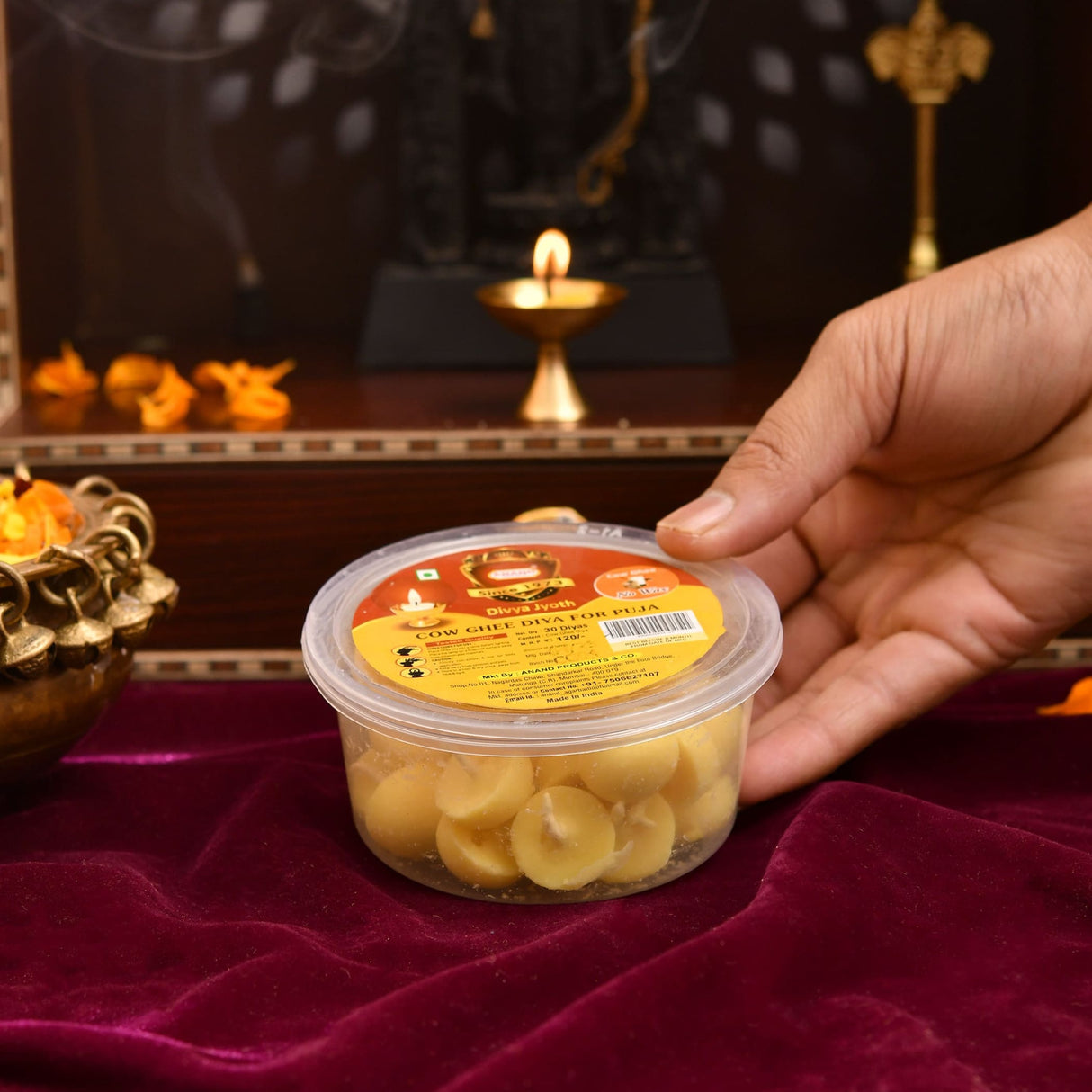 A clear plastic container of round pale yellow pure cow ghee diyas with cotton wicks for puja and temple use