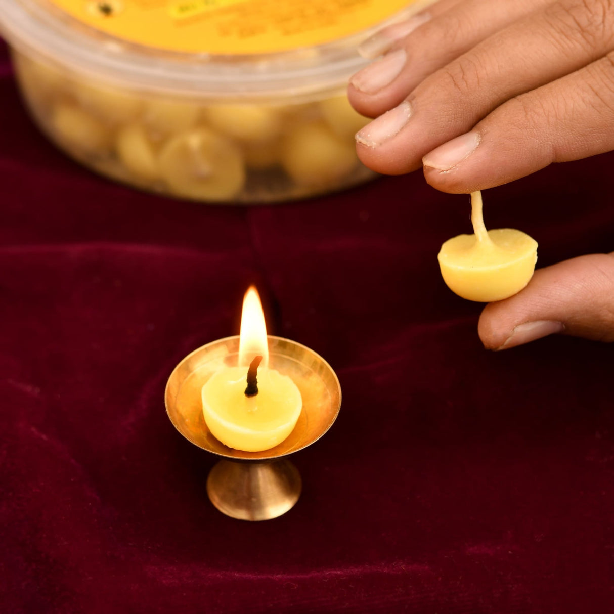 A golden brass oil lamp with a lit yellow beeswax candle using pure cow ghee wick for pooja diya batti and pujan