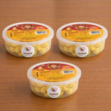 Three clear plastic containers of yellow cow ghee diyas sealed with red and gold labels for pooja and diwali use
