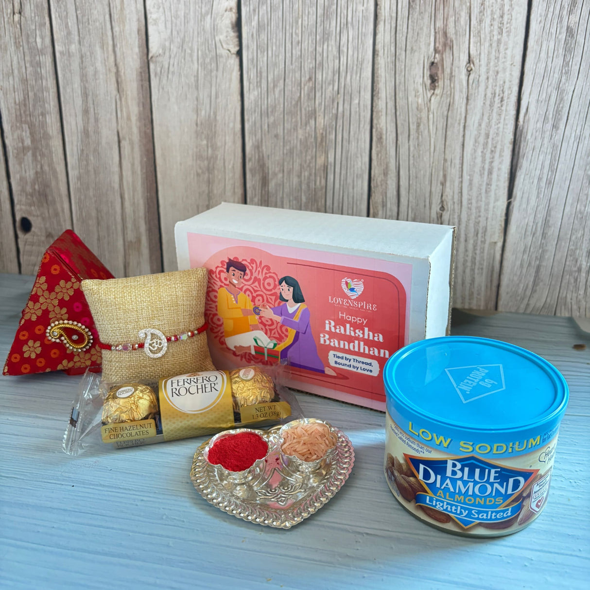 Gold-colored burlap cushion with red beaded pure silver om rakhi bracelet in gift hamper for brother