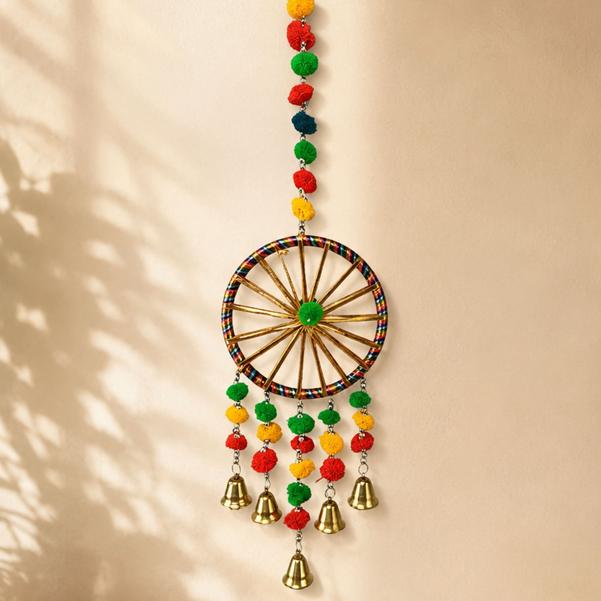 A colorful rajasthani ring wall hanging with pompom and brass bells for traditional home office decor and diwali gift