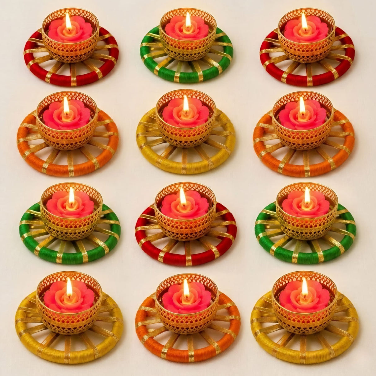 Gold-colored woven tealight candle holders with pink rose-shaped candles on red green and orange yarn bases for festive decor