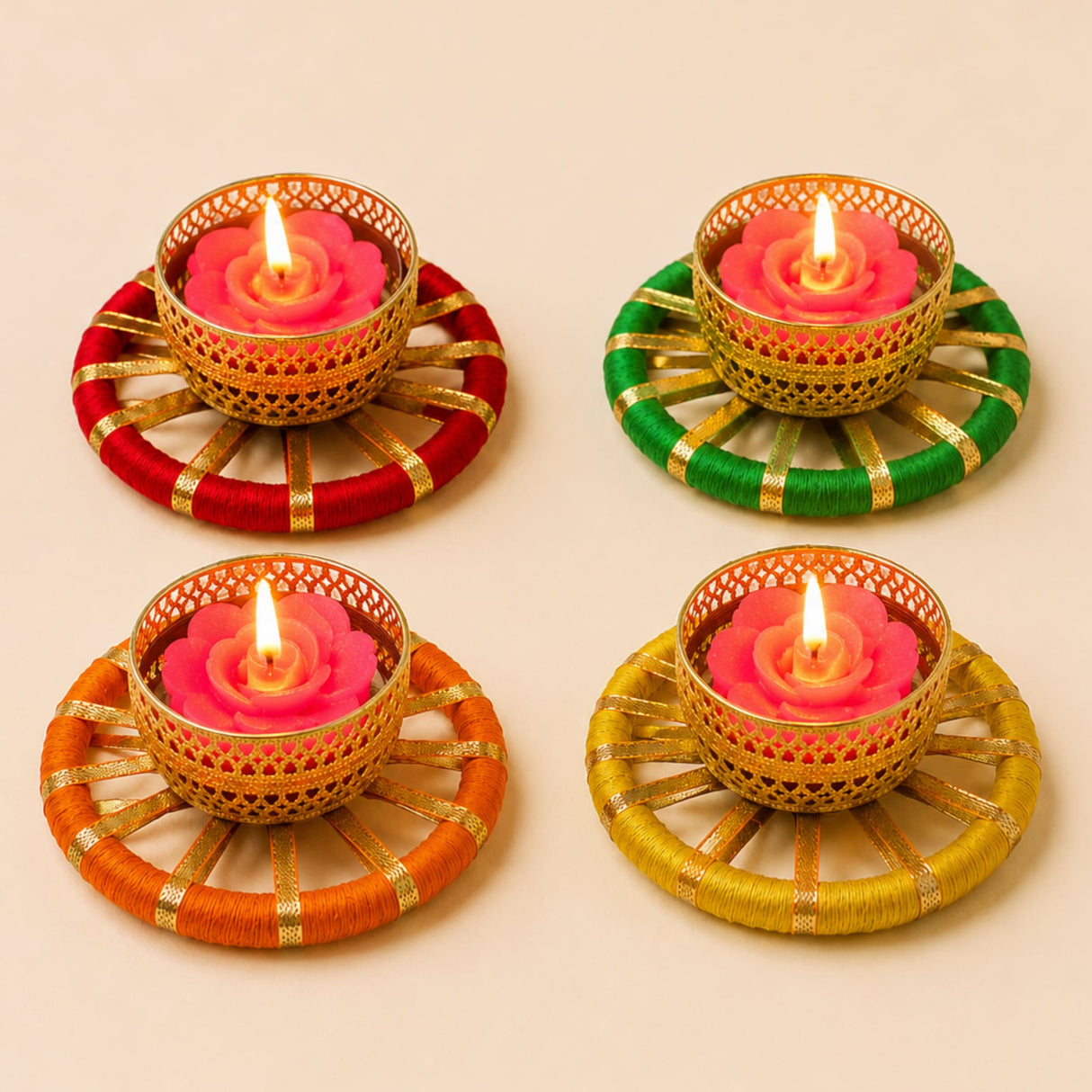 Set of four golden metal tealight candle holders with pink rose wax candles and colorful yarn bases for festive decor