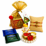 Gold-colored decorative rakhi gift hamper box with intricate red and gold patterns tied with a yellow organza bow