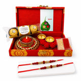 Brocade gift box in red and gold contains two traditional handmade rakhi chocolates candle and decorative items for raksha bandhan