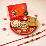 Red decorative pooja thali plate with intricate white green and gold floral patterns in raksha bandhan gift hamper set