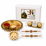 Golden ornate rakhi gift hamper with meenakari pooja thali set, two floral rakhi bracelets, chocolates, and pearl candle holder