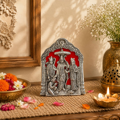 Silver ornate metal Ram Darbar statue with intricate detailing on red background for pooja and home decor