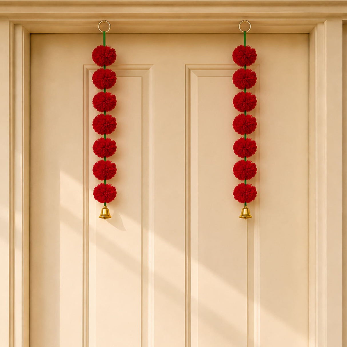 Red marigold toran garland with red pom-poms and gold bells hanging from a door for indian wedding and diwali decor
