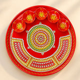 Vibrant red handmade pooja thali with intricate gold green white beadwork and six matching diya bowls for rituals