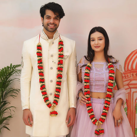 Couple in matching red gold floral velvet varmala garlands with tassels