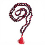 A deep maroon wooden 108 beads red sandalwood mala necklace with red cord and matching tassel for meditation and yoga
