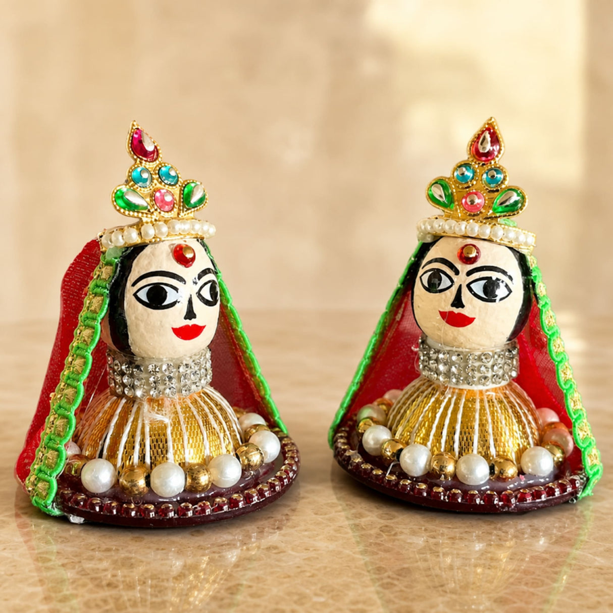 Two intricately decorated goddess riddhi siddhi idols with jeweled crowns and pearl embellishments for pooja decor