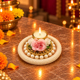 A gold-plated tea light candle holder adorned with white pearls and pink and white artificial flowers for festive decor