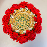A circular floral decorative diya with red artificial roses, gold and green embroidery, and white flowers for Diwali decor