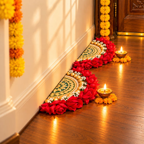 A vibrant red rose garland with gold and white floral embellishments on an artificial green and gold rangoli mat for Diwali decor