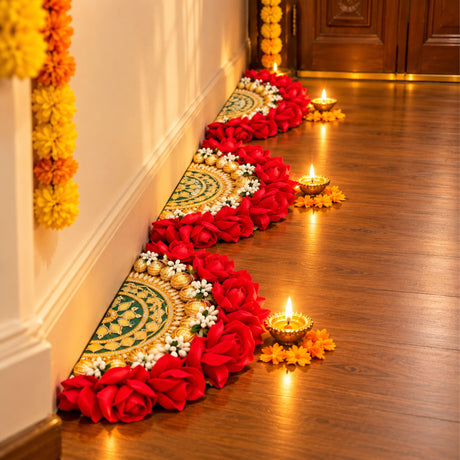 A vibrant red and gold floral decorative rose rangoli centrepiece with artificial embroidered green and gold mat on wooden floor
