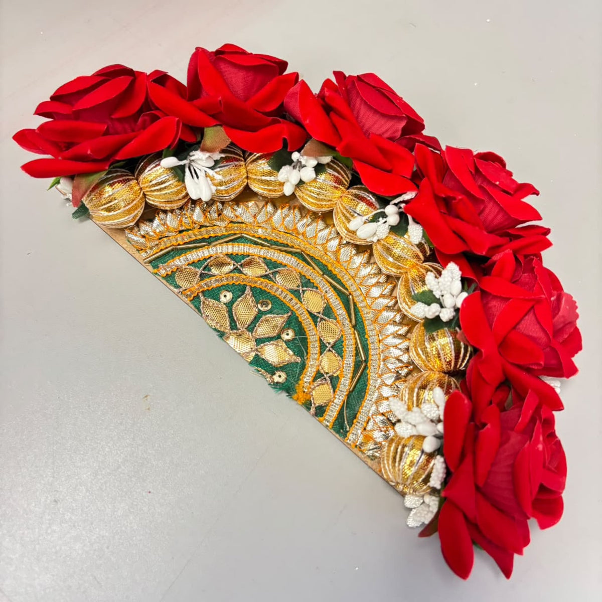 A vibrant red floral decorative fan with gold and green embroidered patterns for diwali rangoli centerpiece decor