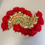 A vibrant red floral decorative rose rangoli centrepiece with gold and green embroidered patterns for Diwali decor