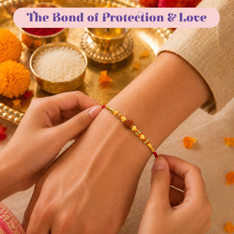 A red thread rakhi with gold-colored beads and a central rudraksha bead for raksha bandhan gift hamper