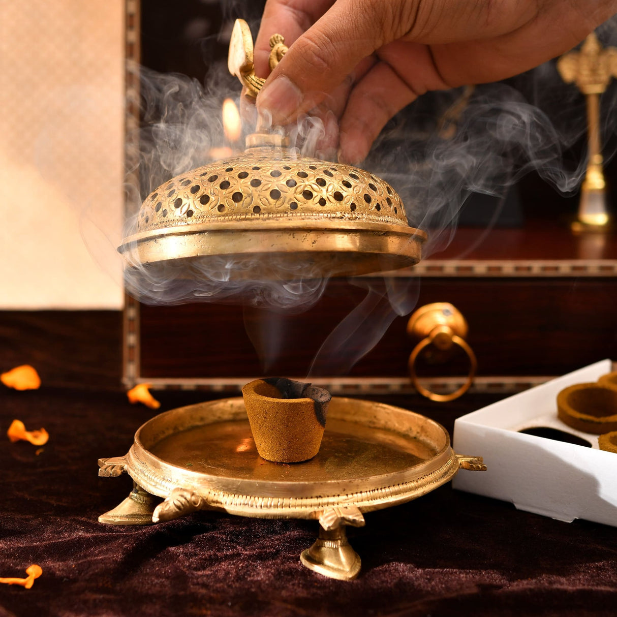 Golden brass incense burner with floral perforations emitting smoke