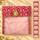 A vibrant pink and gold embroidered fabric saree cover with button closure and decorative golden flower clasp for storage